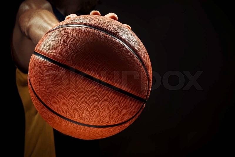 The silhouette view of a basketball player holding basket ball on black background. The hands and ball close up, stock photo
