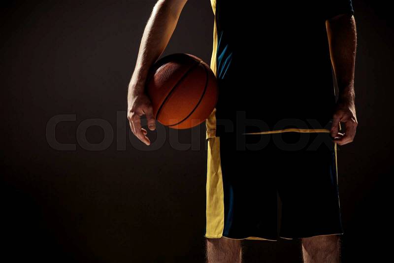 The silhouette view of a basketball player holding basket ball on black background, stock photo
