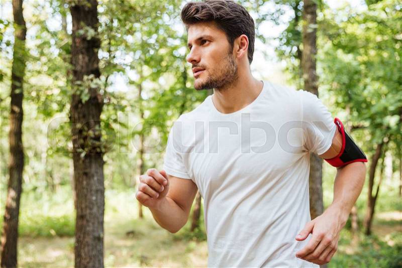Handsome young man athlete running in forest, stock photo