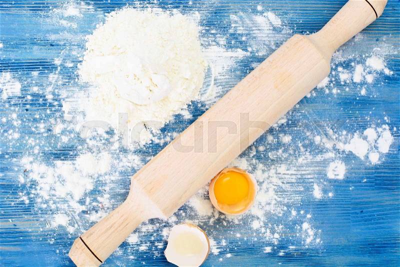 Flour, Eggs and Rolling Pin on a Blue Background Studio Photo, stock photo