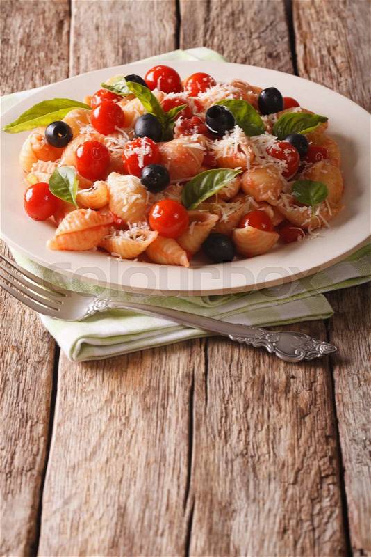 Italian cuisine: pasta with tomatoes, olives and parmesan cheese on a plate close-up. vertical\, stock photo