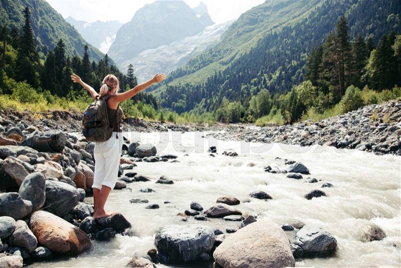Backpacker walking by the river. Traveler standing and looking at beautiful view, stock photo