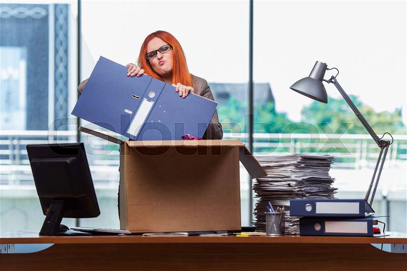 The red head woman moving to new office packing her belongings, stock photo