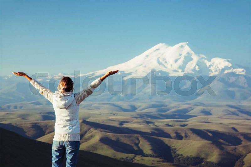 Traveler standing on top of Bermamyt plateau and looking on Elbrus mountain. Karachay-Cherkessia, Caucasus, Russia, stock photo