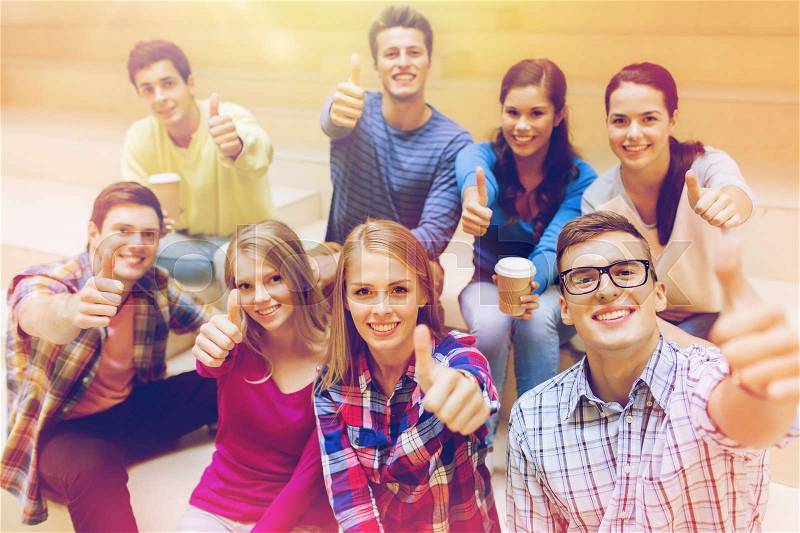 Education, high school, friendship, drinks and people concept - group of smiling students with paper coffee cups showing thumbs up gesture, stock photo