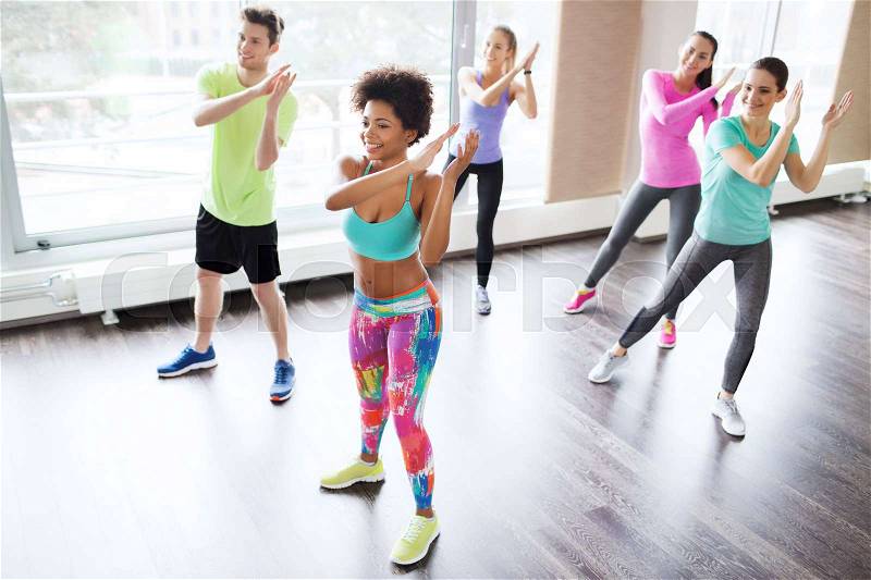 Fitness, sport, dance and lifestyle concept - group of smiling people with coach dancing in gym or studio, stock photo