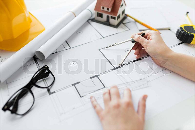 Business, architecture, building, construction and people concept - close up of architect hands with compass measuring living house blueprint, stock photo