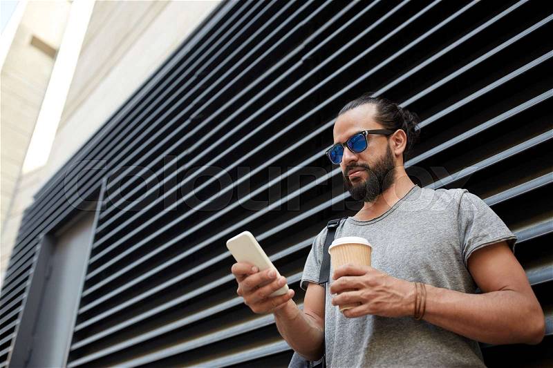 Travel, tourism, communication, technology and people concept - man with backpack and coffee cup texting on smartphone on city street, stock photo