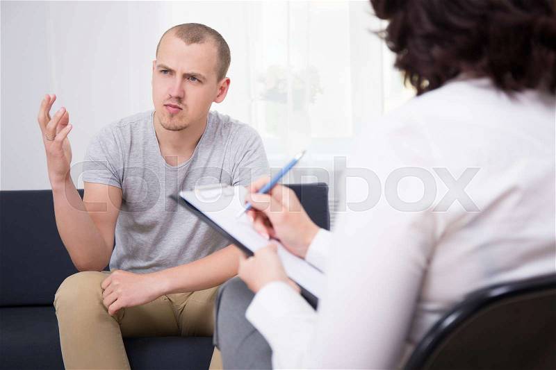 Portrait of happy young man talking about something at interview in modern office, stock photo