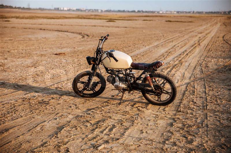 Retro motorcycle standing in the desert, stock photo