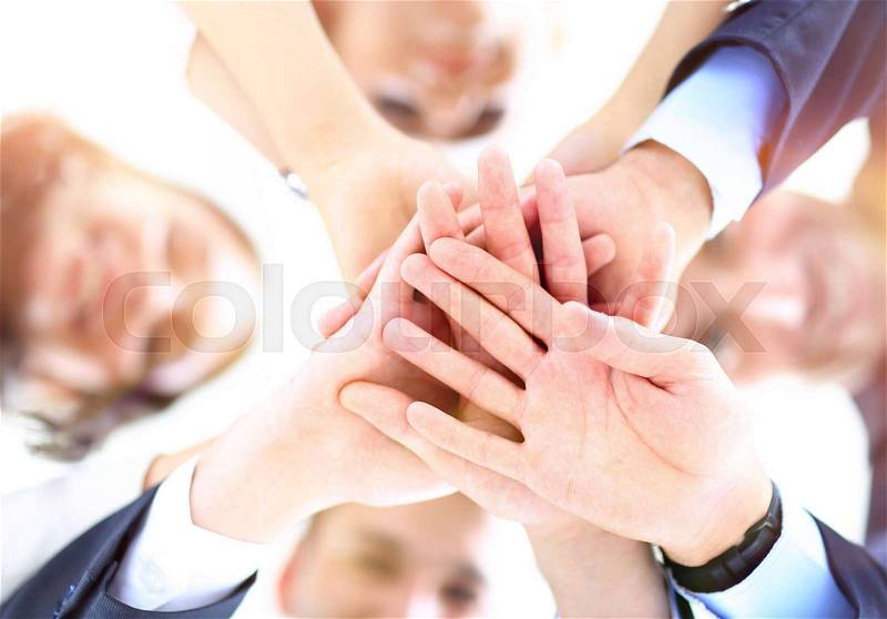 Small group of business people joining hands, low angle view, stock photo