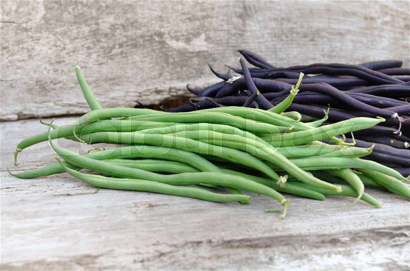 Fresh green and violet beans on a wooden plank, stock photo