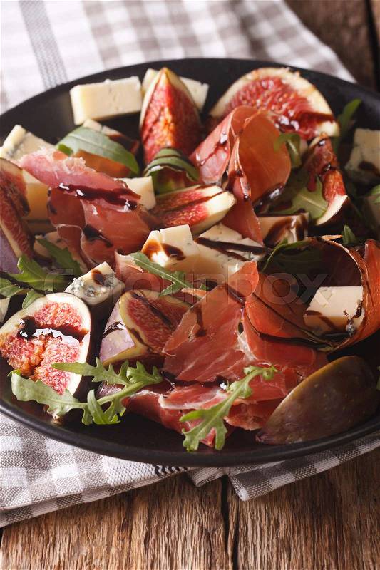 Gourmet salad with figs, prosciutto, blue cheese and arugula close-up on a plate on the table. vertical\, stock photo