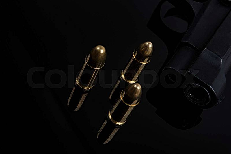 Gold bullets and gun on black background, stock photo