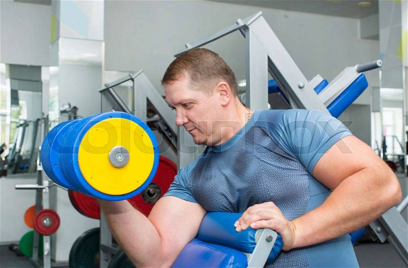 Adult brutal man is engaged in sports bodybuilding, stock photo