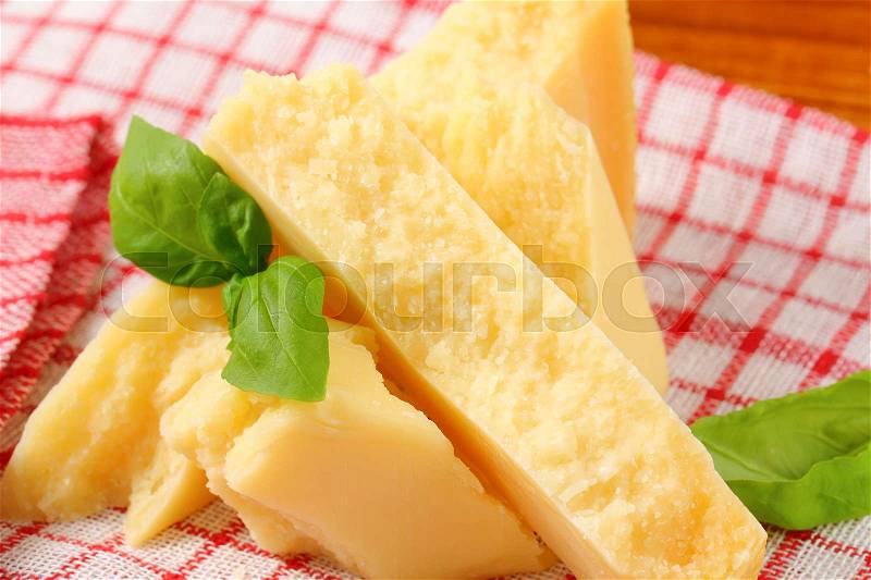 Pieces of Parmesan cheese on checked tea towel, stock photo