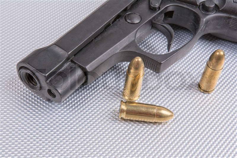 Gold bullets and gun on aluminium background, stock photo