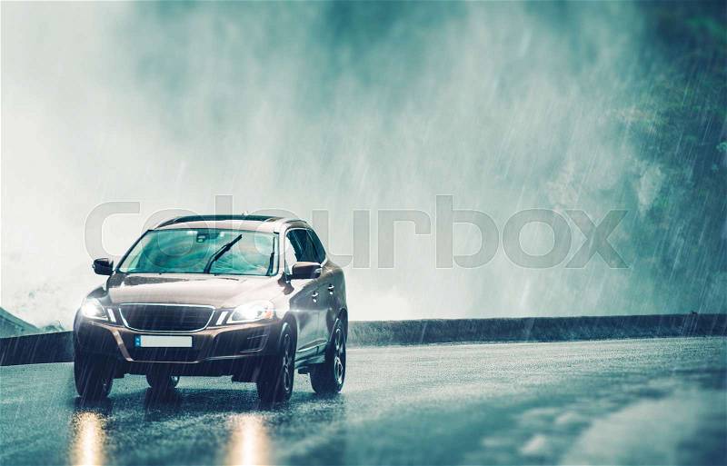 Driving Car in Heavy Rain. Modern Compact SUV Car Speeding on the Wet Road, stock photo
