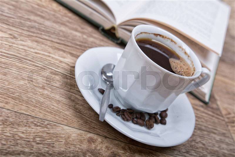 A cup of coffee with a book on a wooden background, stock photo