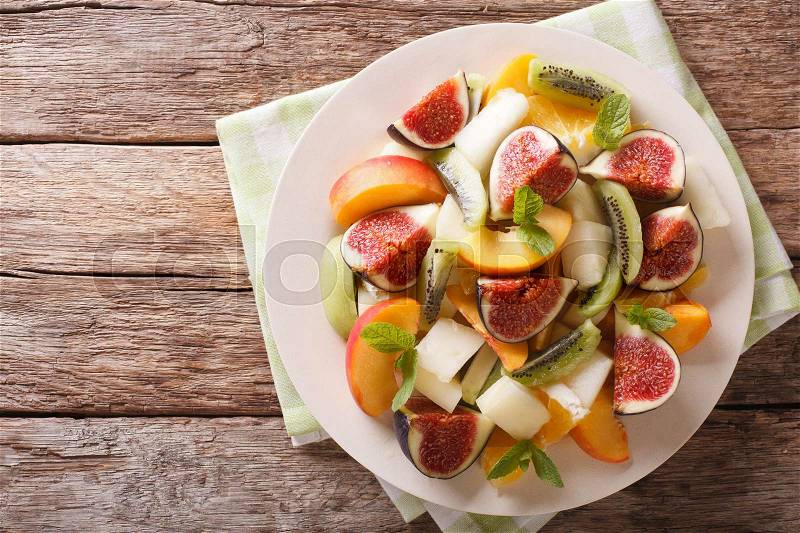 Healthy Fruit salad with fig, peach, melon, kiwi and orange close-up on the table. horizontal view from above , stock photo