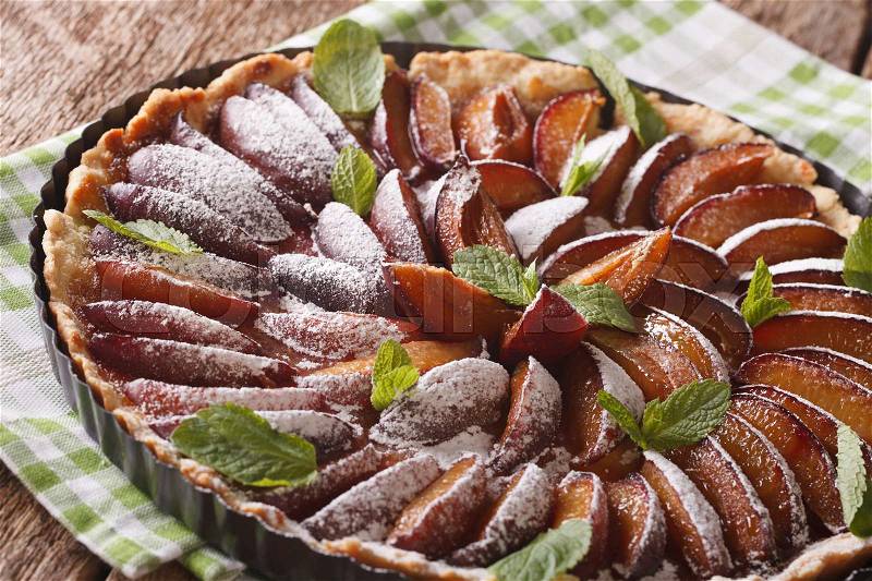 Plum cake with mint and powdered sugar close-up on the table. horizontal , stock photo