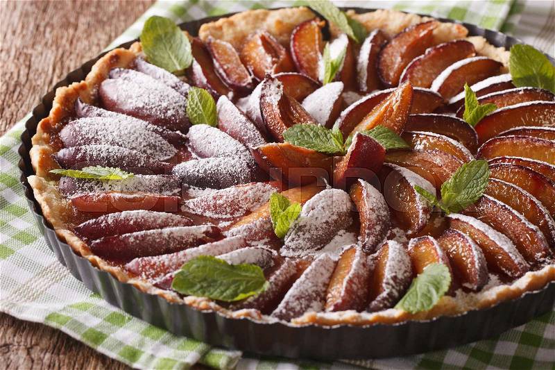 Delicious pastry: plum tart with mint and powdered sugar close-up on the table. horizontal , stock photo