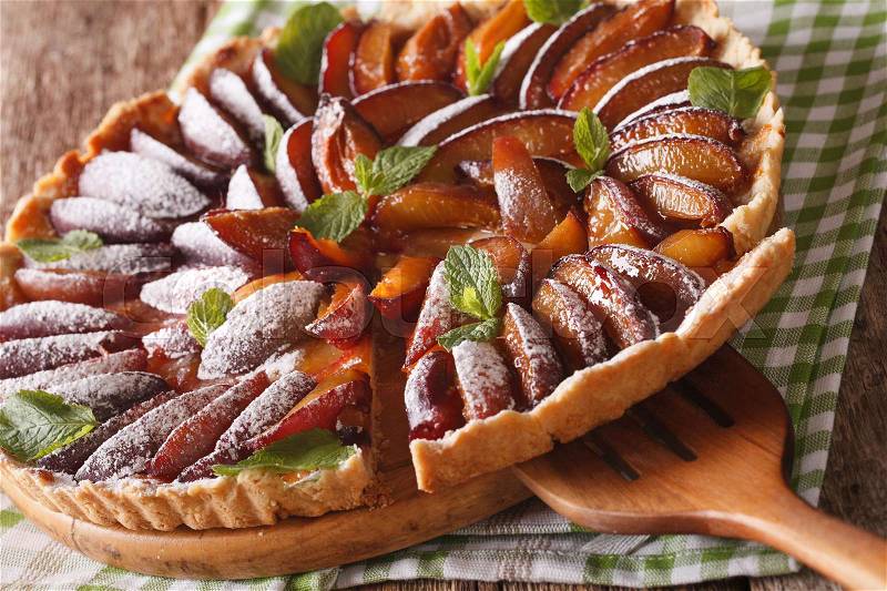 Freshly baked sliced tart of ripe plums close-up on the table. horizontal , stock photo