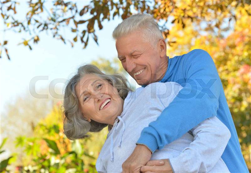 Portrait of a happy senior couple in autumn park, stock photo