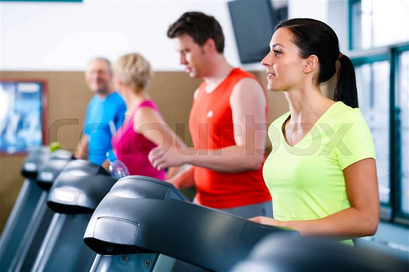 Group of young and senior men and women on treadmill in gym running, stock photo