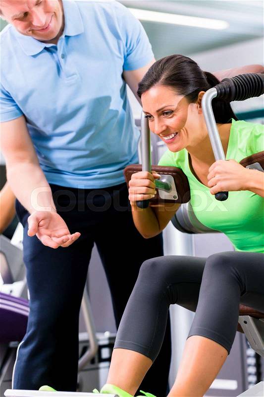 Woman with personal trainer doing sport und fitness in gym, he is showing her the training plan, stock photo