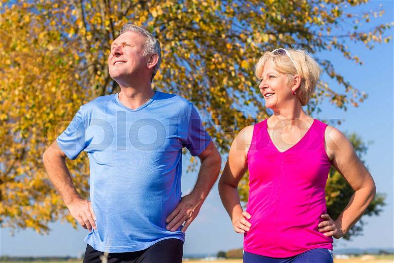 Woman and man, seniors, doing sport outdoors in the grass on meadow, stock photo