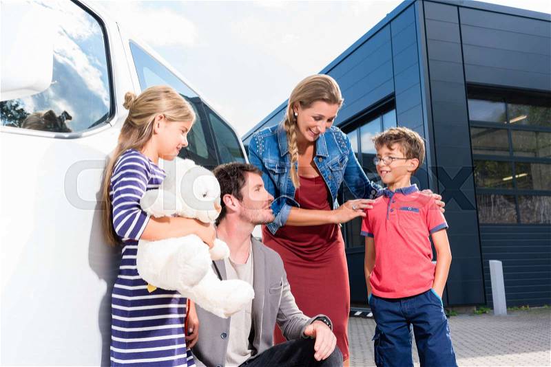 Family with children buying auto at car dealer standing in front of new van, stock photo