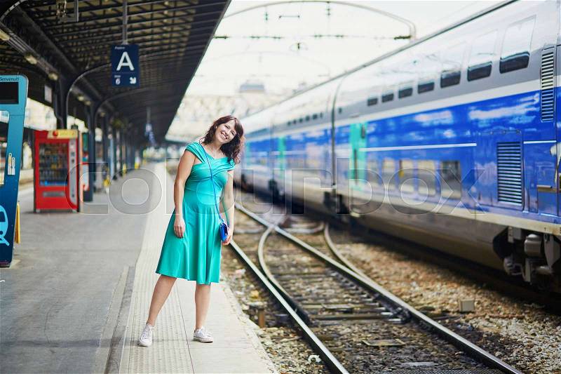 Young woman in Paris waiting for a train on railway station. Local French commuter going to work or vacation. Tourist using subway or intercity train in France, stock photo