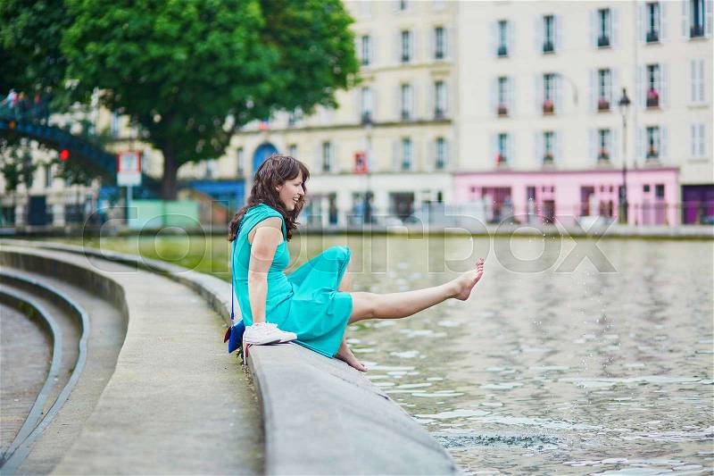 Cheerful young French woman having fun on Saint-Martin canal in Paris on a summer day, stock photo