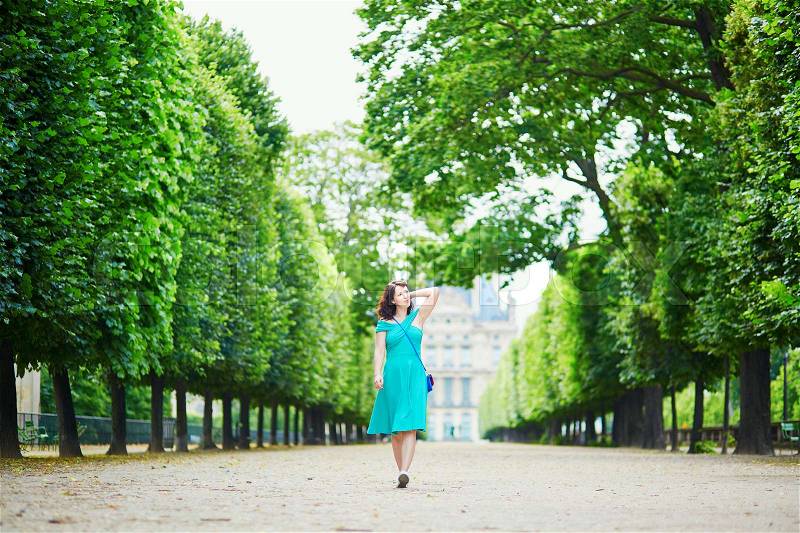 Beautiful young woman walking in Parisian Tuileries park on a summer day, stock photo