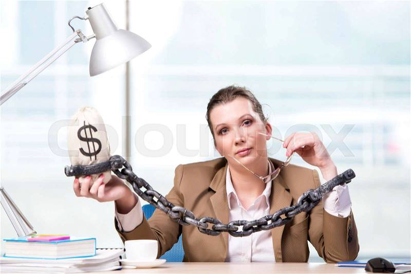 Woman chained to her working desk, stock photo