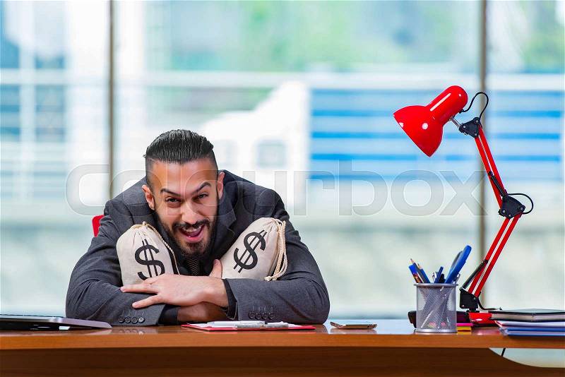 Happy businessman with money sacks in the office, stock photo