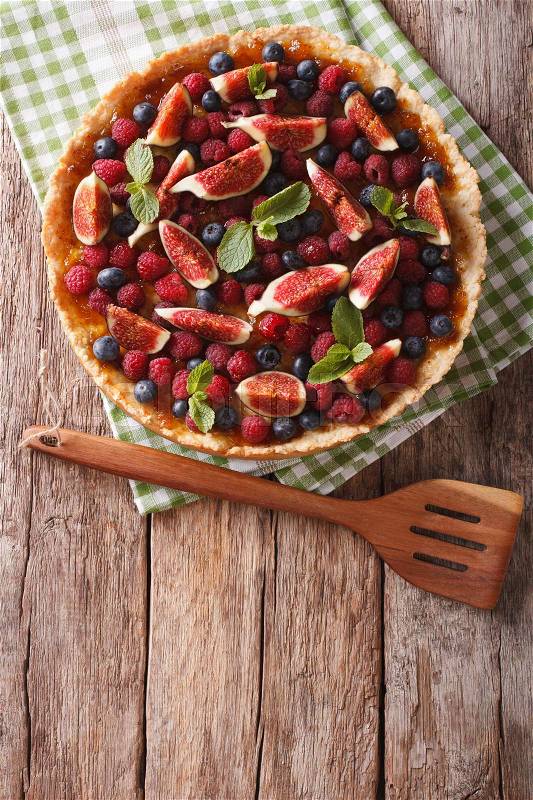 Freshly baked cake with fresh figs, raspberries and blueberries on the table. Vertical view from above\, stock photo