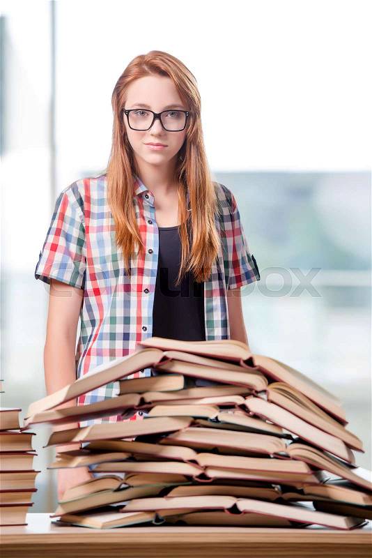 Student with stacks of books preparing for exams, stock photo