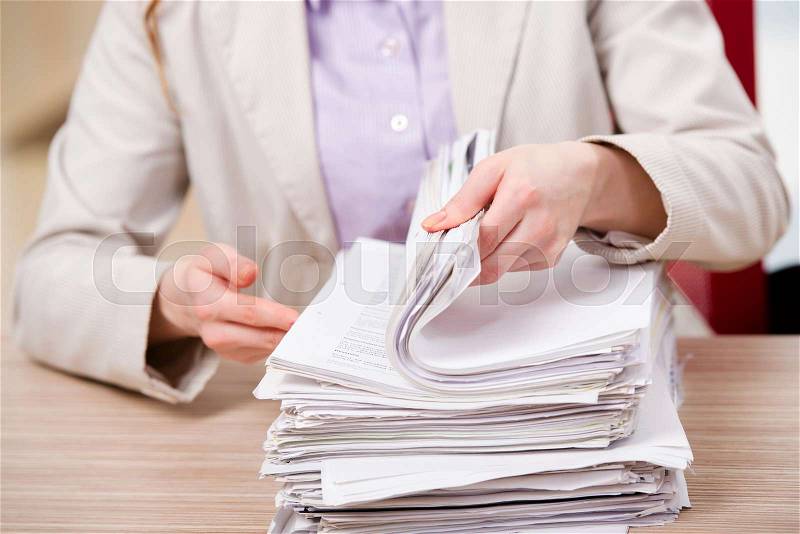 Businesswoman working with stack of papers, stock photo