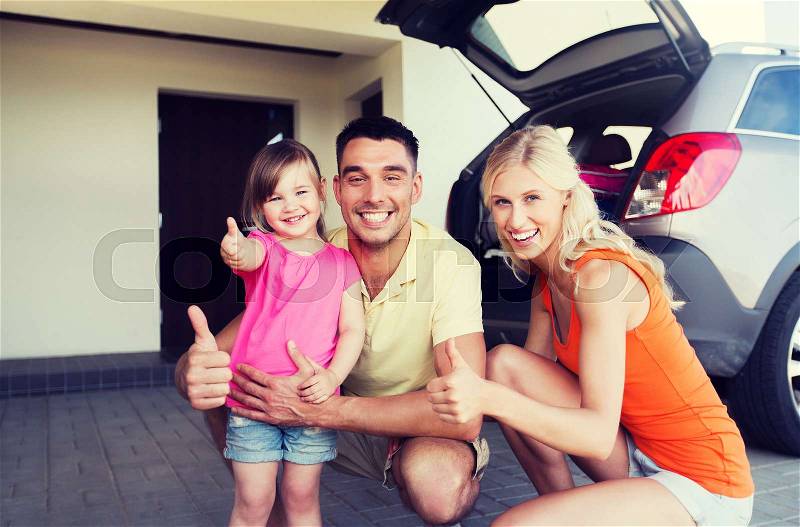 Transport, leisure, road trip and people concept - happy family with little girl and hatchback car showing thumbs up at home parking space, stock photo