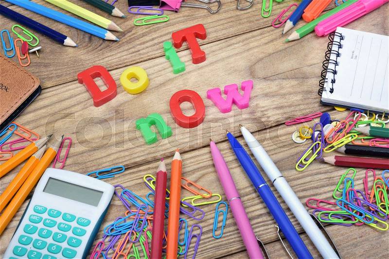 Do it now text and office tools on wooden table, stock photo
