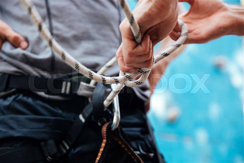 Close-up of rock climber putting on safety harness and climbing equipment outdoors, stock photo