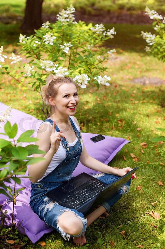 Distance work or education concept. Young woman freelancer have an idea using notebook outdoors pointing finger up, stock photo