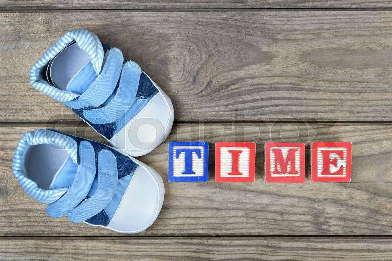 Kid shoes and word time on wooden table, stock photo