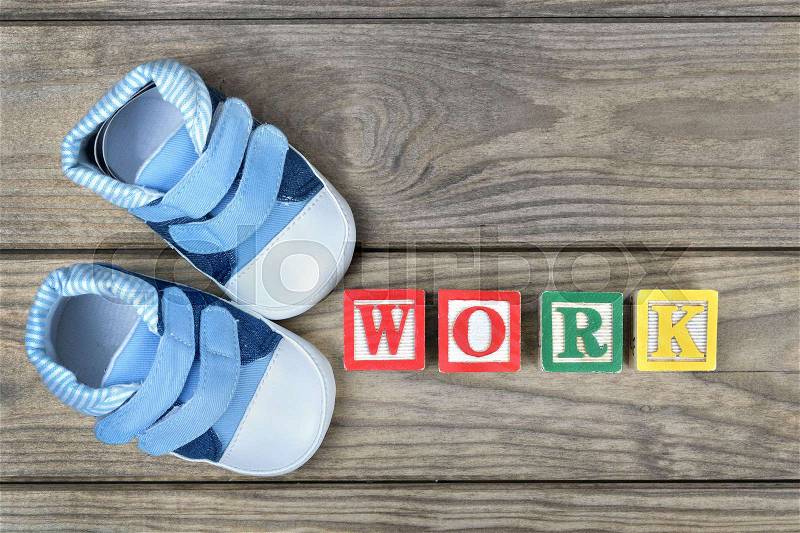 Kid shoes and word work on wooden table, stock photo