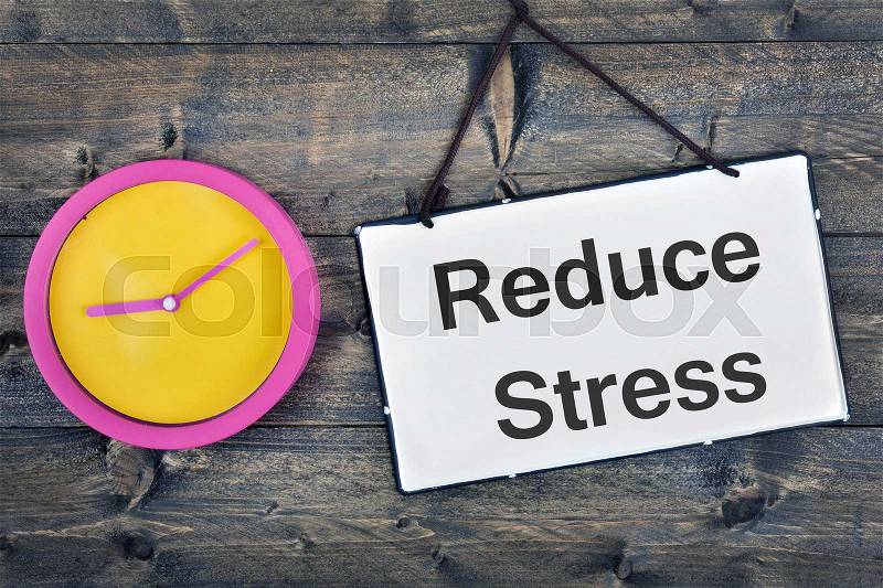 Reduce Stress sign and clock on wooden table, stock photo