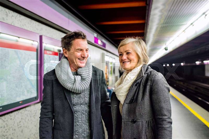 Beautiful senior couple standing at the underground platform, waiting, stock photo