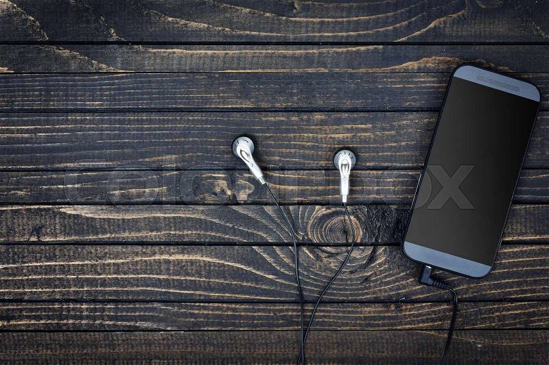 Phone and earphones on wooden table, stock photo