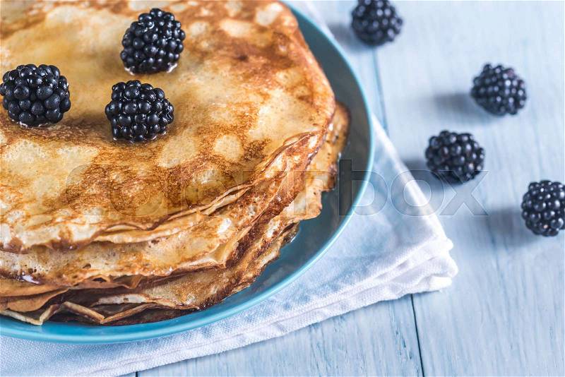 Crepes with blackberries on the wooden table, stock photo